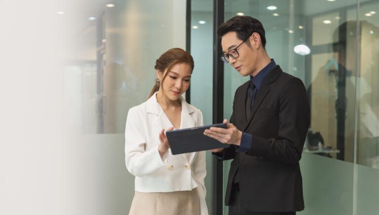 Smiling asian businesswoman showing tablet to her manager during